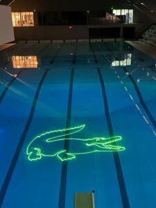 Europe Évènement - Photo of a swimming pool with a logo in the shape of a crocodile (Lacoste) projected at the bottom of the water