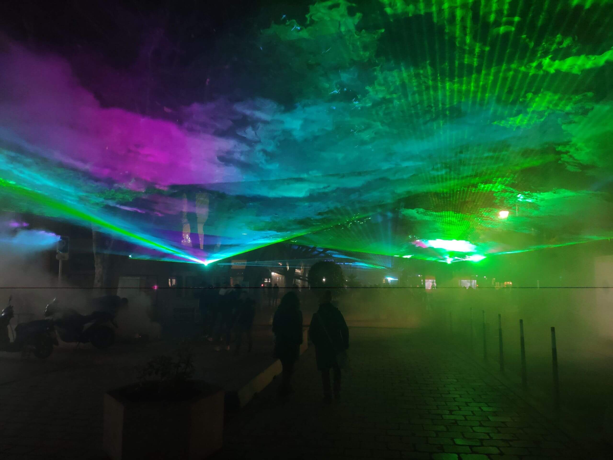 Europe Évènement - Laser show - Photo of a city centre with a blue, green and pink aurora borealis in the sky