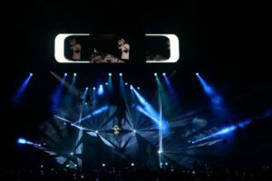 Europe Évènement - Photo d'un concert du DJ David Guetta avec faisceaux lasers et lumières bleus autour de lui